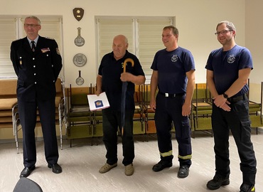 Immer gut behütet mit dem Schirm des Kreis&shy;feuerwehr&shy;verbandes, den es zur Auszeichnung mit dazu gab. Überbracht vom Vorstand für Jugendarebeit Stefan Kothe. (links) Wehrführer Rico Nowka und sein Stellvertreter Nico Hammel gratulieren.