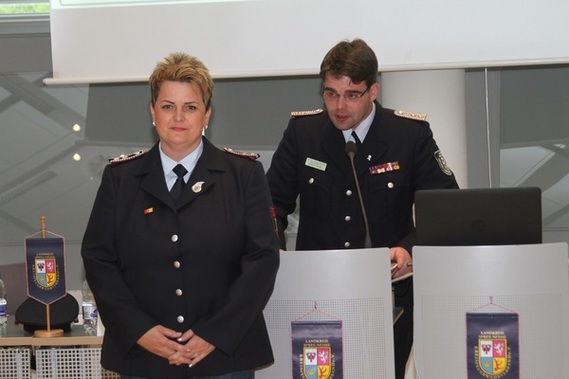 Robert Buder (Hintergrund) verliest die Urkunde zu Auszeichnung der ehemaligen Schatzmeisterin der Kreis&shy;jugend&shy;feuerwehr Spree-Neiße