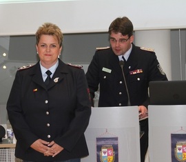 Robert Buder (Hintergrund) verliest die Urkunde zu Auszeichnung der ehemaligen Schatzmeisterin der Kreis&shy;jugend&shy;feuerwehr Spree-Neiße