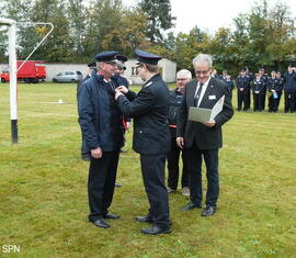 Kreis&shy;jugend&shy;feuerwehrwart Christian Rösiger übergibt Bernd Schulze das Ehrenzeichen der Landesjugendfeuerwehr Brandenburg in Bronze aus.