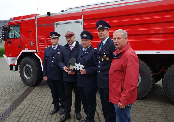 Im Beisein von Amtswehrführer Marcus Weber (l.) und dem Vorsitzenden des Amtsausschusses, Joachim Dieke (r.) übergibt Amtsdirektor Tobias Hentschel (2. v. l.) den symbolischen Fahrzeugschlüssel für das hinter ihnen stehende GTLF an Gerätewart Jens Buder (m.) und Ortswehrführer Daniel Scheiter.