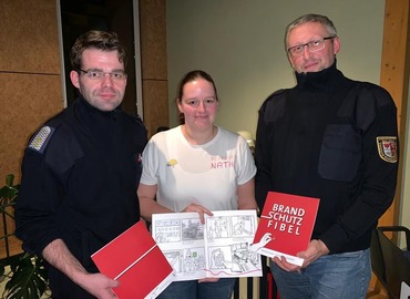 Robert Buder (Vorsitzender KFV), Nathalie Scherer (Brandenburgs beliebteste Brandschutzerzieherin) und Stefan Kothe (amt. Kreis&shy;jugend&shy;feuerwehrwart) präsentieren die dt-polnischen Brandschutzfibeln