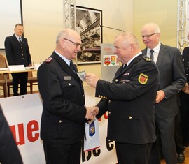 Der Präsident des Landesfeuerwehrverbandes, Werner-Siegwart Schippel, überreicht Siegmund Rückmann das Ärmelabzeichen als Ehrenmitglied