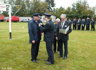 Kreis&shy;jugend&shy;feuerwehrwart Christian Rösiger übergibt Bernd Schulze das Ehrenzeichen der Landesjugendfeuerwehr Brandenburg in Bronze aus.